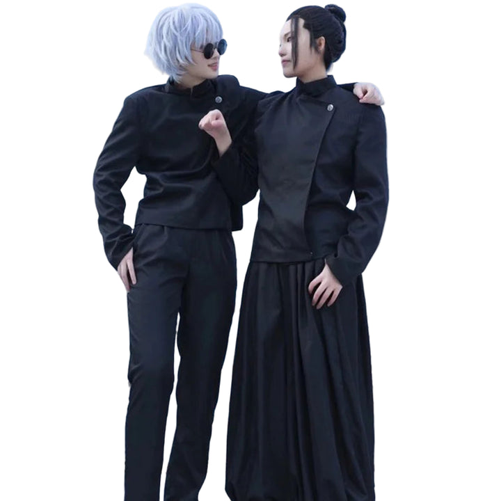 Two people in black outfits standing against a graffiti-covered wall.